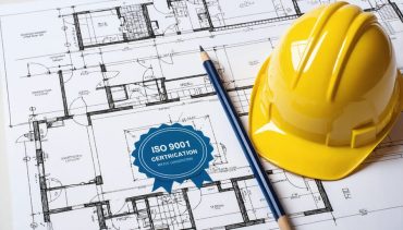 An ISO 9001 certification seal on a construction blueprint background with symbols representing building codes and quality craftsmanship in the construction industry.